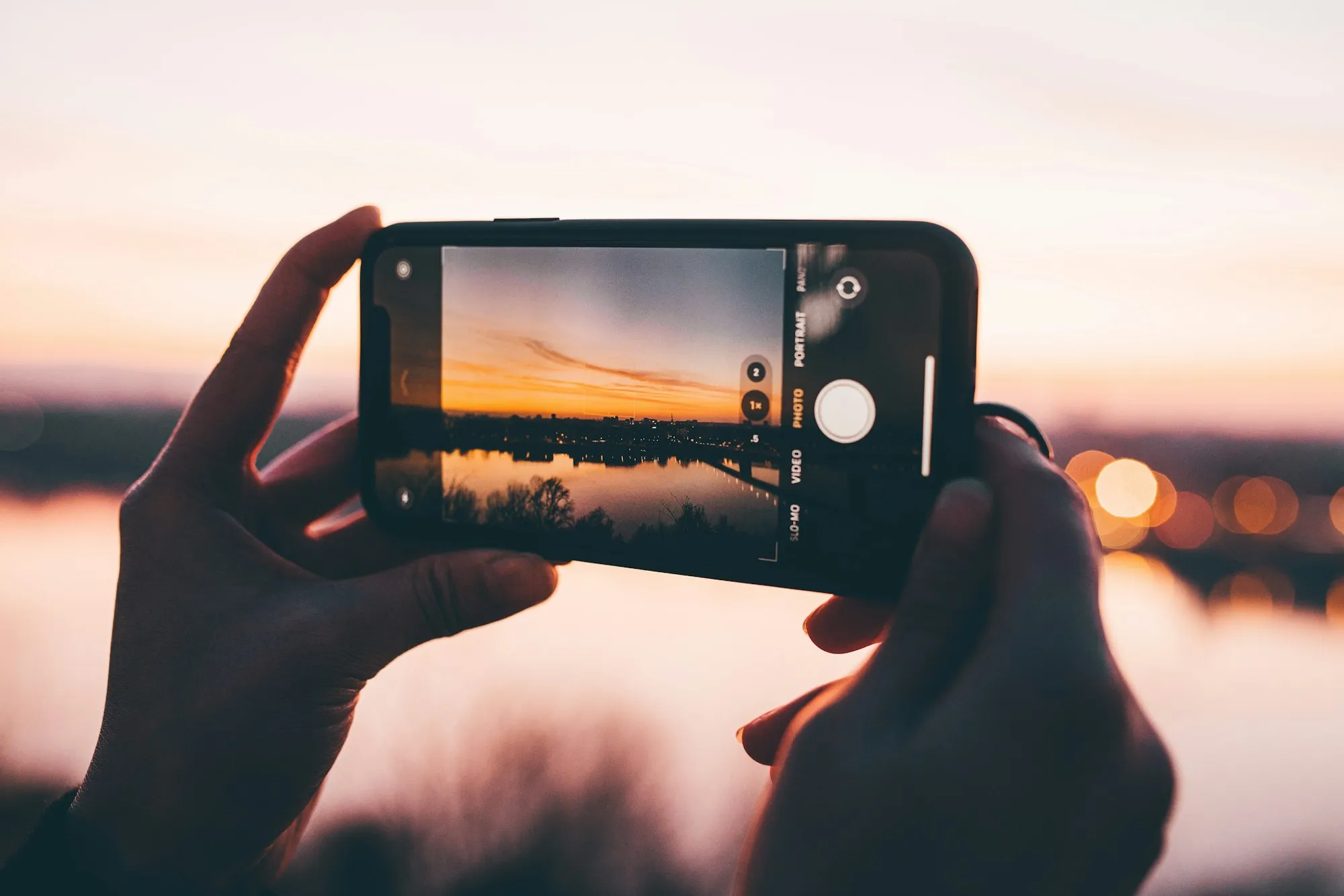 Hände filmen mit dem Smartphone einen Sonnenuntergang