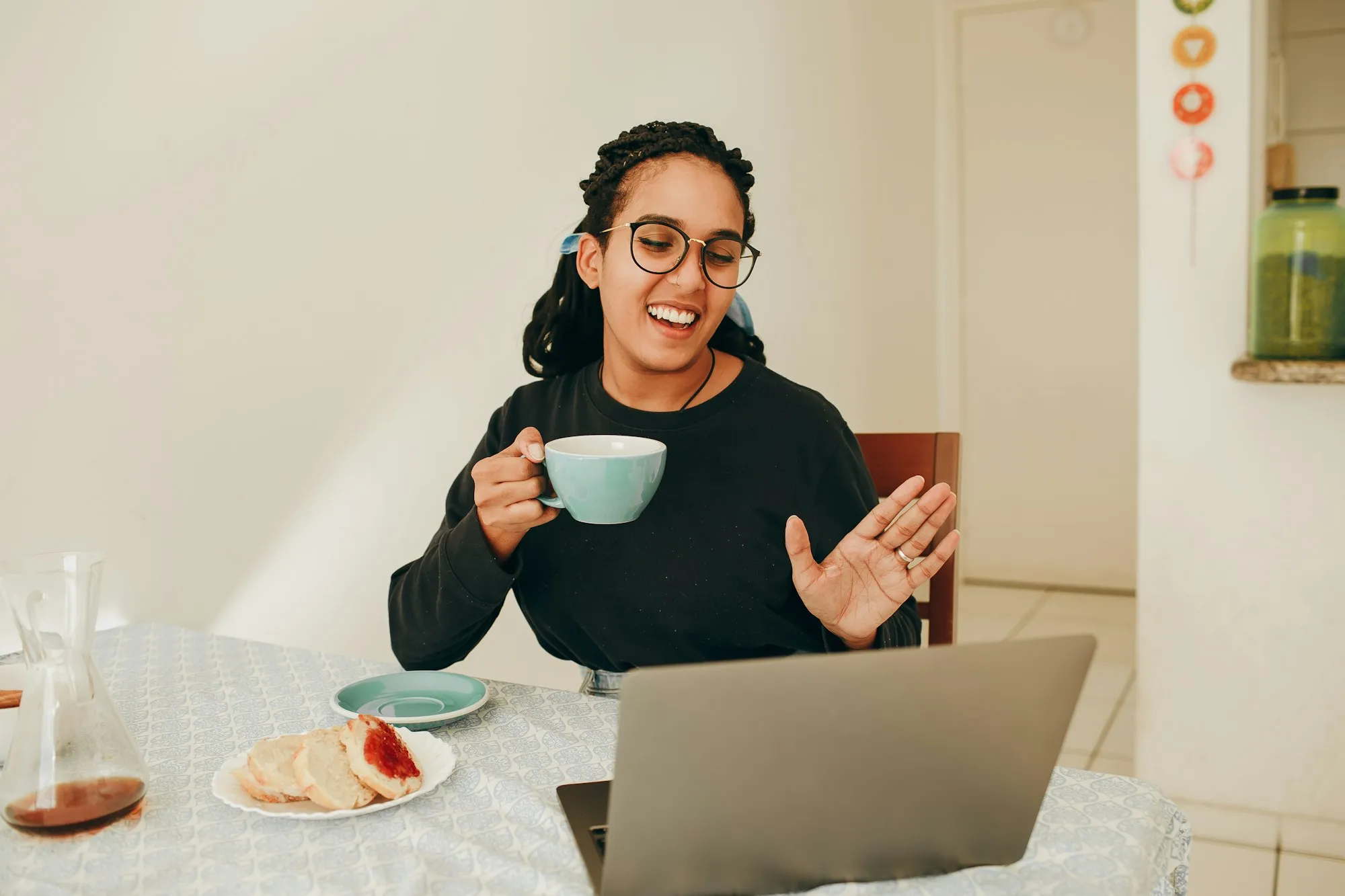 Lächelnde Frau mit Kaffeetasse in einem Videocall